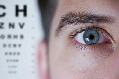 close up of eye with eye exam chart